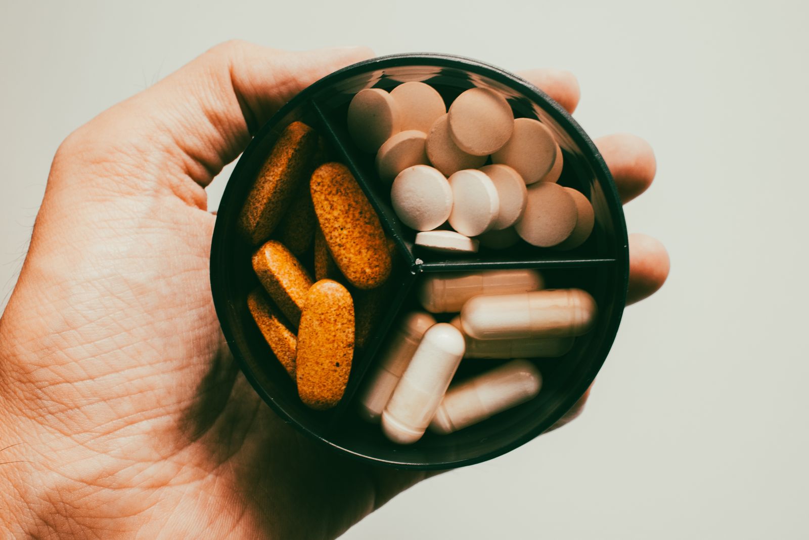 Hand met diverse supplementen voor sportvoeding